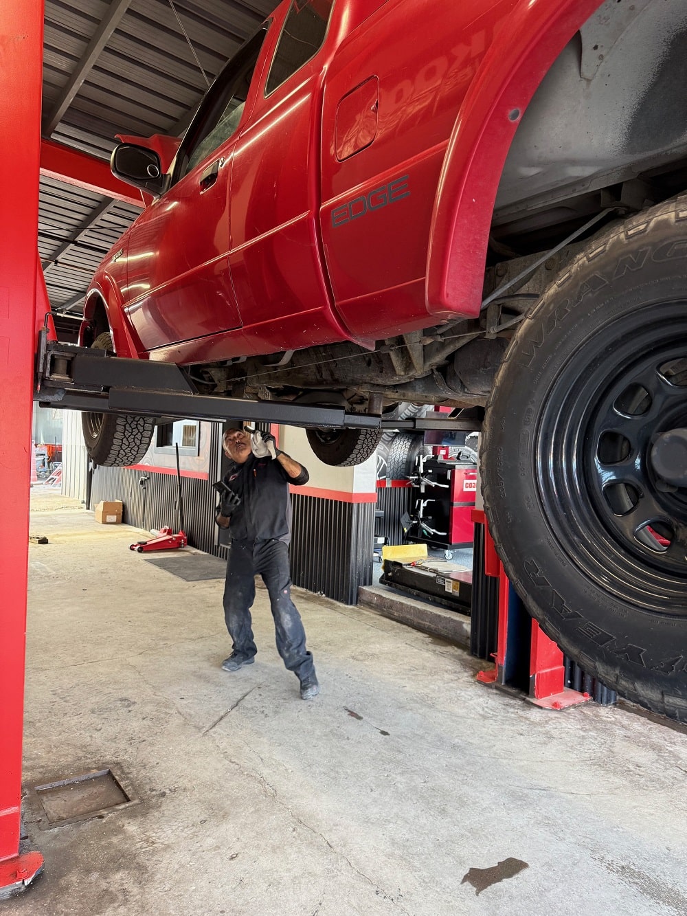 Mechanic conducting general vehicle repairs on a red pick up truck