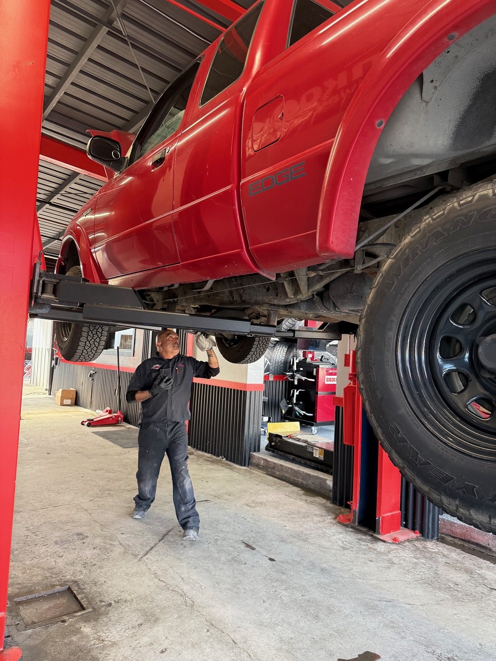 Mechanic conducting general vehicle repairs on a red pick up truck