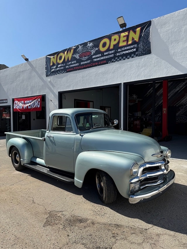 An antique car parked outside an auto repair shop