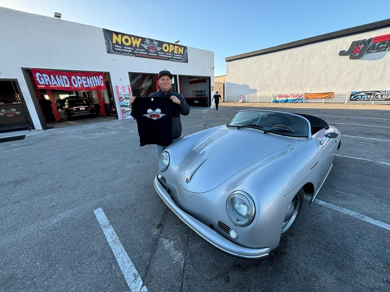 A satisfied customer posing for a picture with his antique car and Pitt Stop Auto's t-shirt in hand